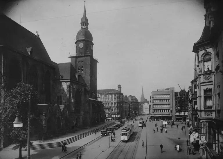 Der alte Friedhof mit der Reinoldikirche um 1930, eine belebte Straßensituation mit Fußgängern, Straßenbahnen und Autos 
