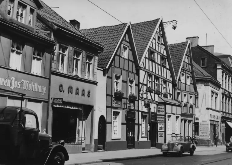 Kuckelke 24-32 in den 1930er Jahren, kleine Geschäfte, Fachwerkhäuser, Autos und Fußgänger prägen das Bild