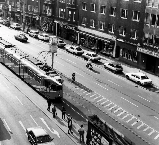 Kuckelke 4-20 im Jahr 1984, belebte Straßensituation mittig fahren Straßenbahnen, Autos rechts und links sowie Fußgänger
