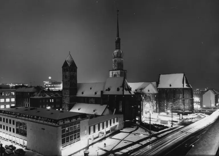 Willy Brandt Platz mit Blick auf die Reinoldikirche in der Nacht, die Dächer und Straßen sind verschneit