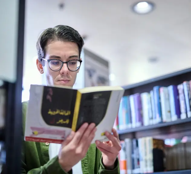Nutzer schaut sich ein arabischsprachiges Buch in der internationalen Bibliothek an