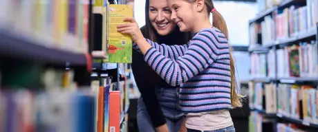 Kind mit Mutter bei der Buchauswahl in der Kinder- und Jugendbibliothek