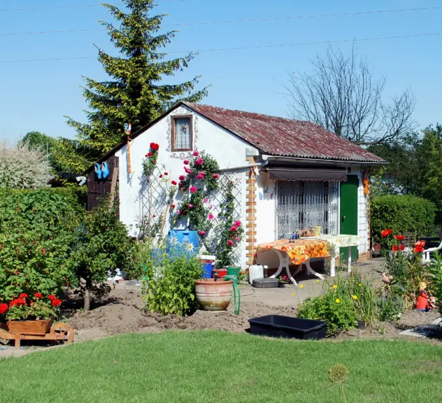 Bild eines Kleingartens mit einem Gartenhaus und vielen Pflanzen
