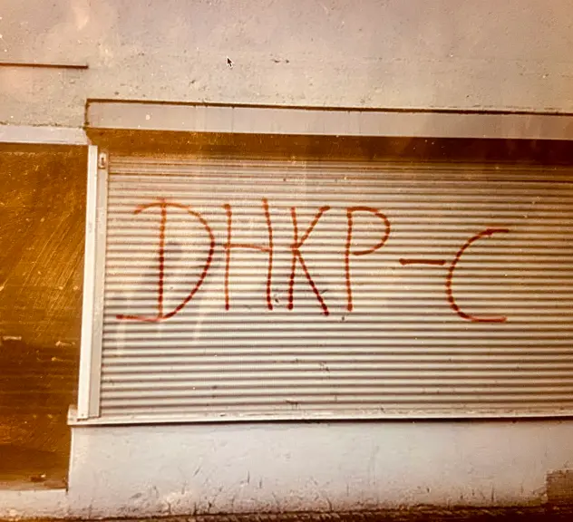 Foto einer geschlossenen Rollade, die mit den Buchstaben "DHKP-C" besprüht ist.