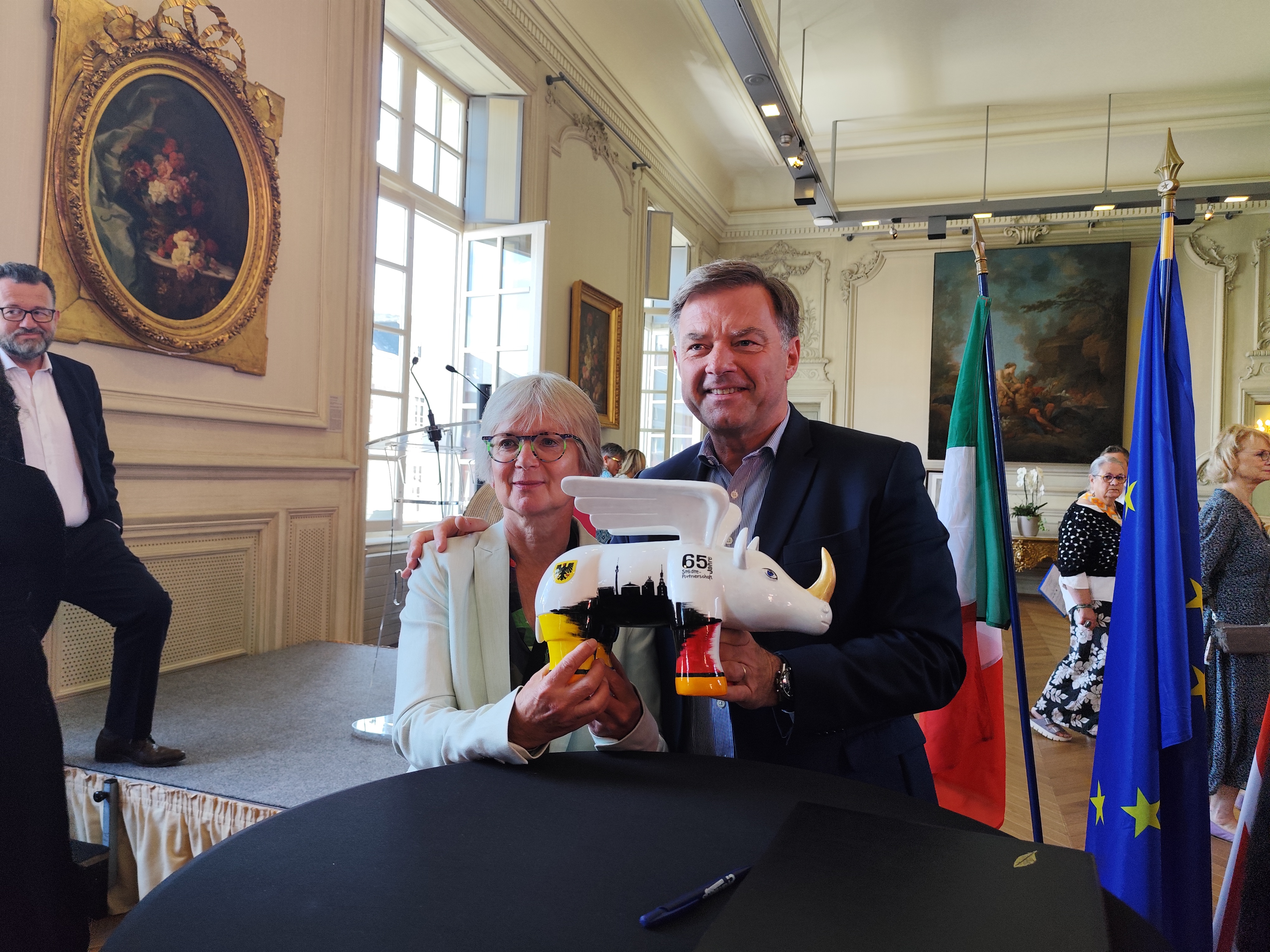 Frau Brunsing und Herr de Jenlis posieren im Rathaus mit einem Nashorn.